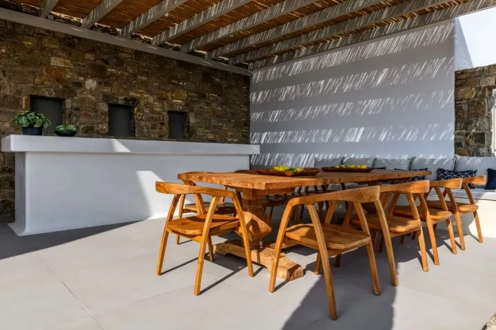 A covered outdoor dining area with a wooden table and seating.