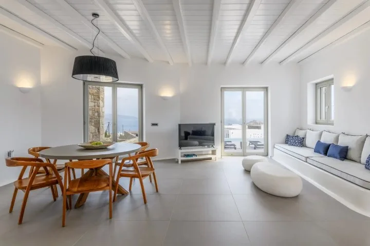 A bright living and dining area with a table, seating, and ocean views.