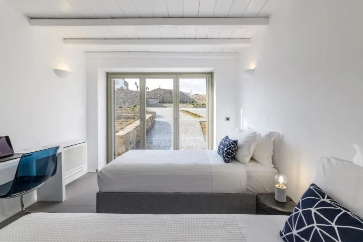 A bright bedroom with a bed beside glass doors opening onto a patio.