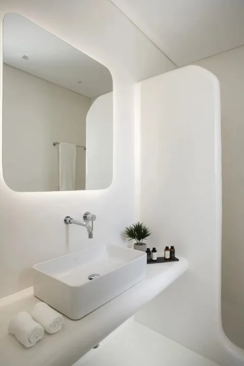 A bright bathroom vanity with a vessel sink, mirror, and toiletries.
