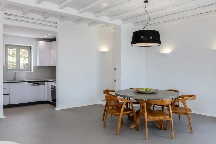 A dining area with a wooden table and seating beside an open kitchen.