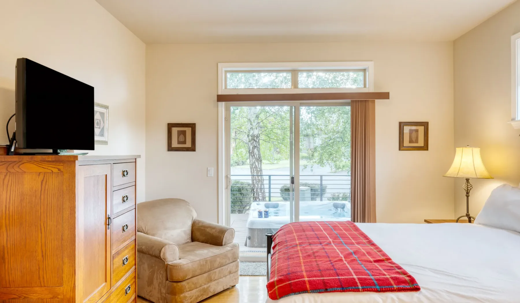 A bedroom with a bed, a television, and a large window overlooking greenery.