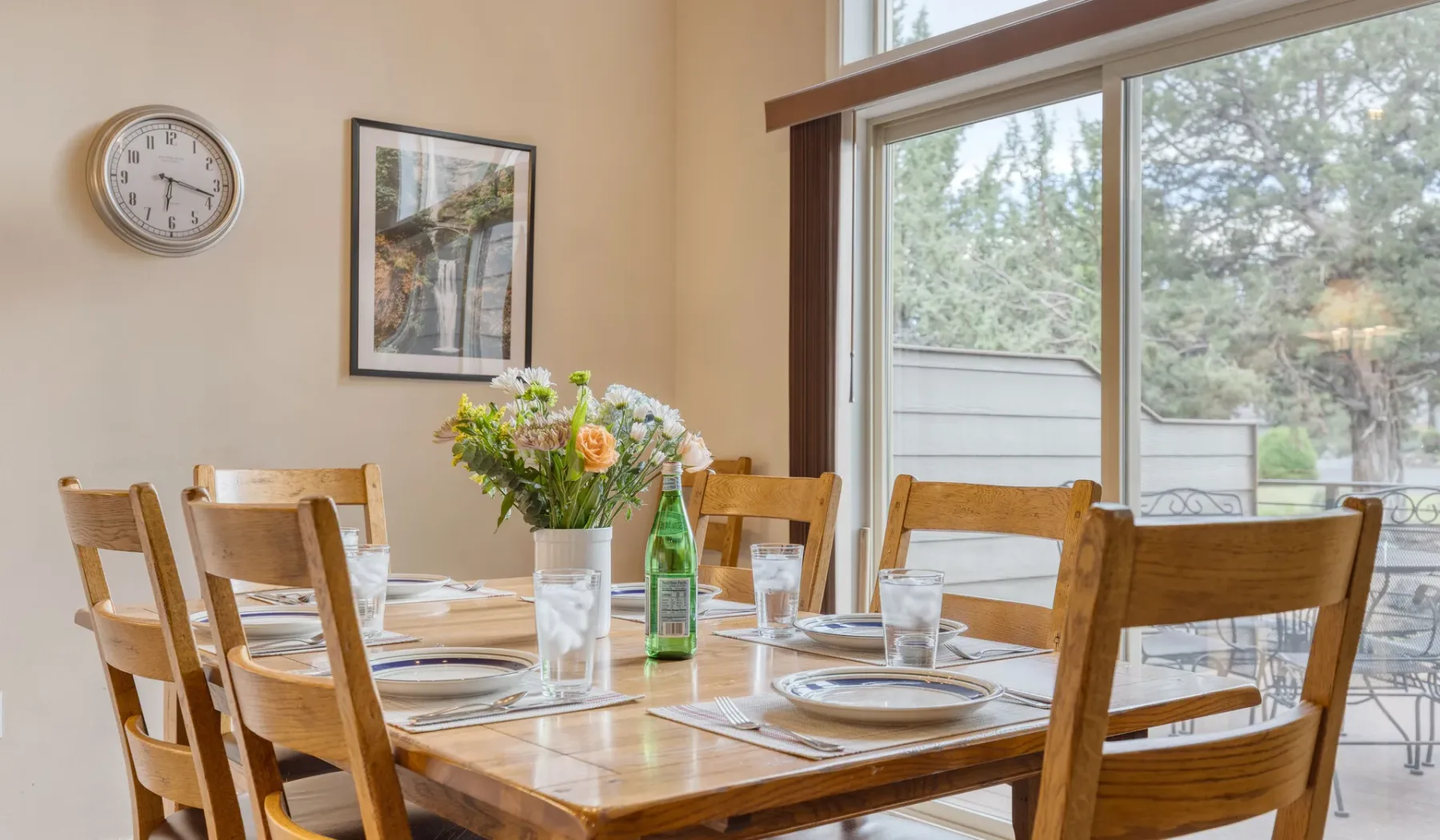A dining area with a wooden table set beside large windows.