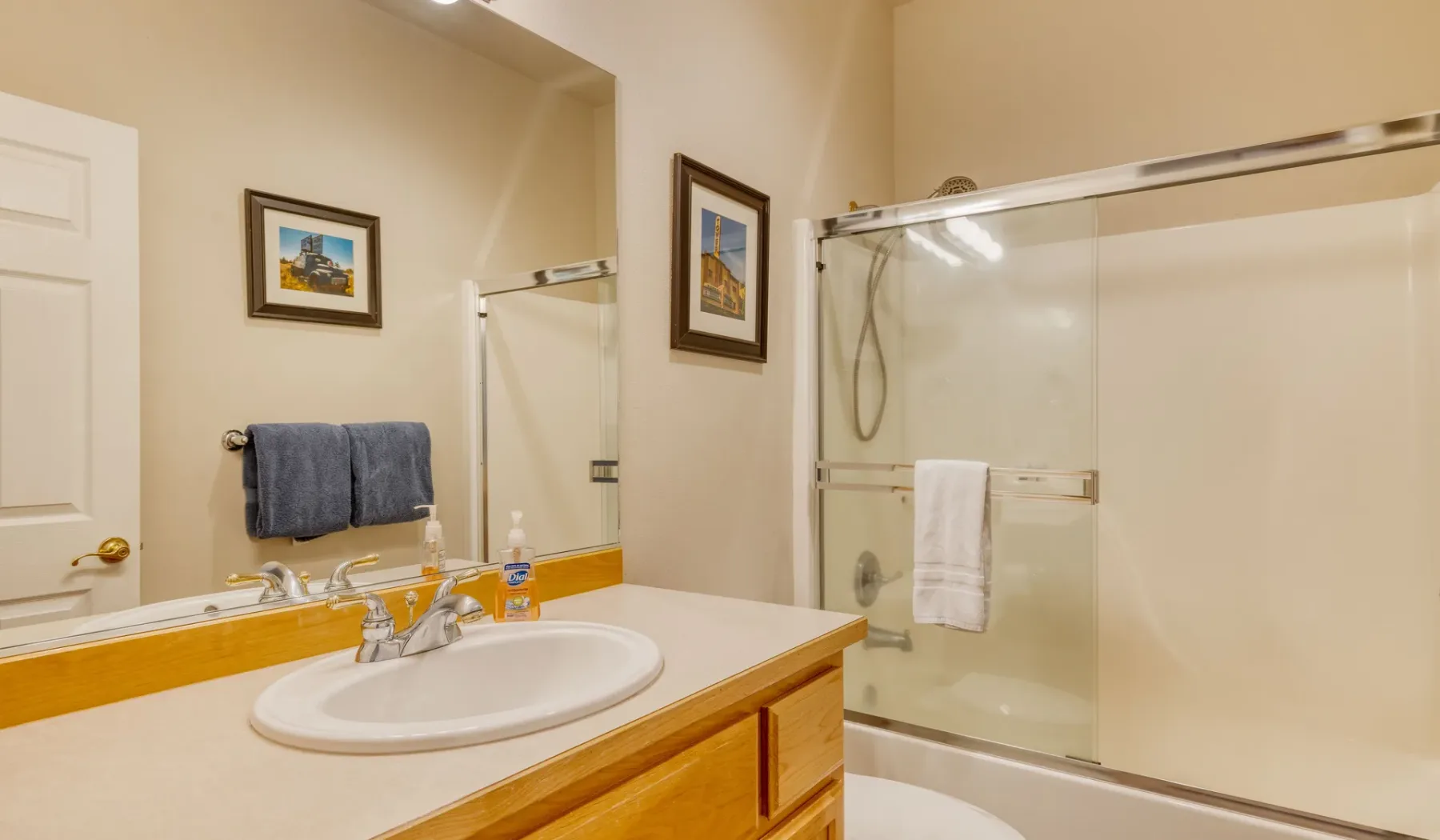 A bathroom with a vanity sink and a glass-enclosed shower.