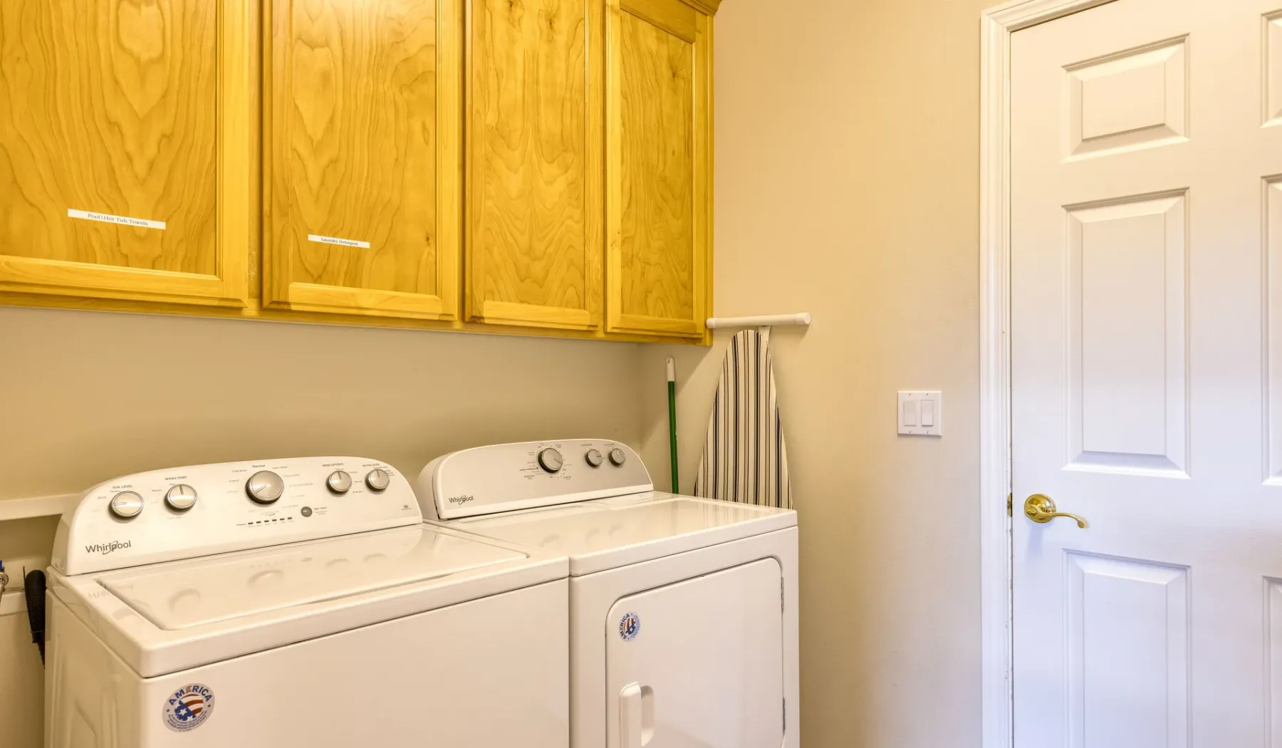 A laundry area with a washer and dryer beneath wooden cabinets.