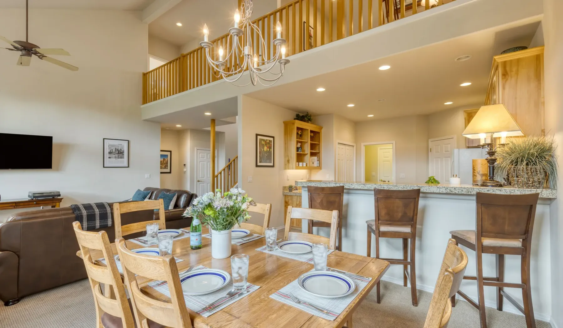 An open-plan living and dining area with a kitchen bar and upper-level railing.