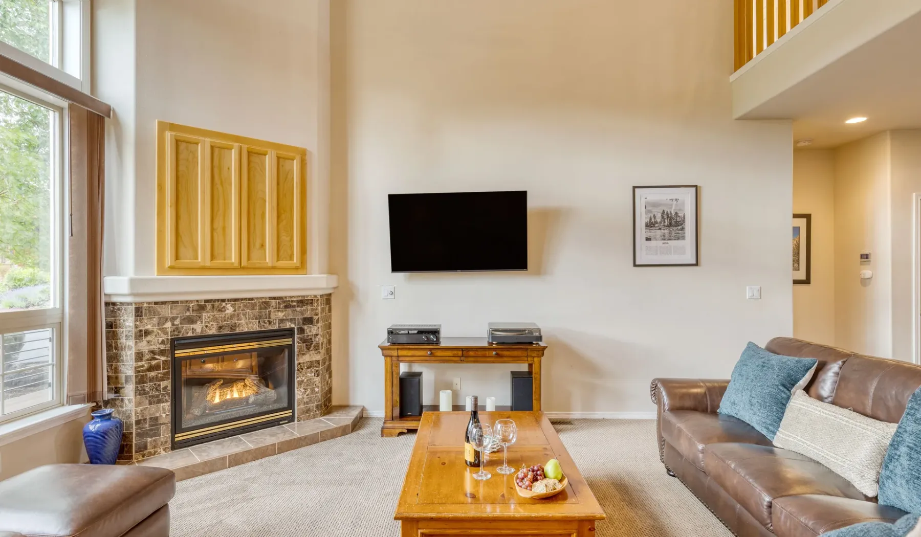 A bright living room with a fireplace, wall-mounted television, and seating.