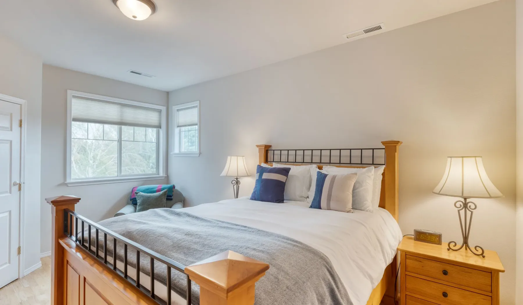 A bedroom with a large bed, bedside tables, and windows.