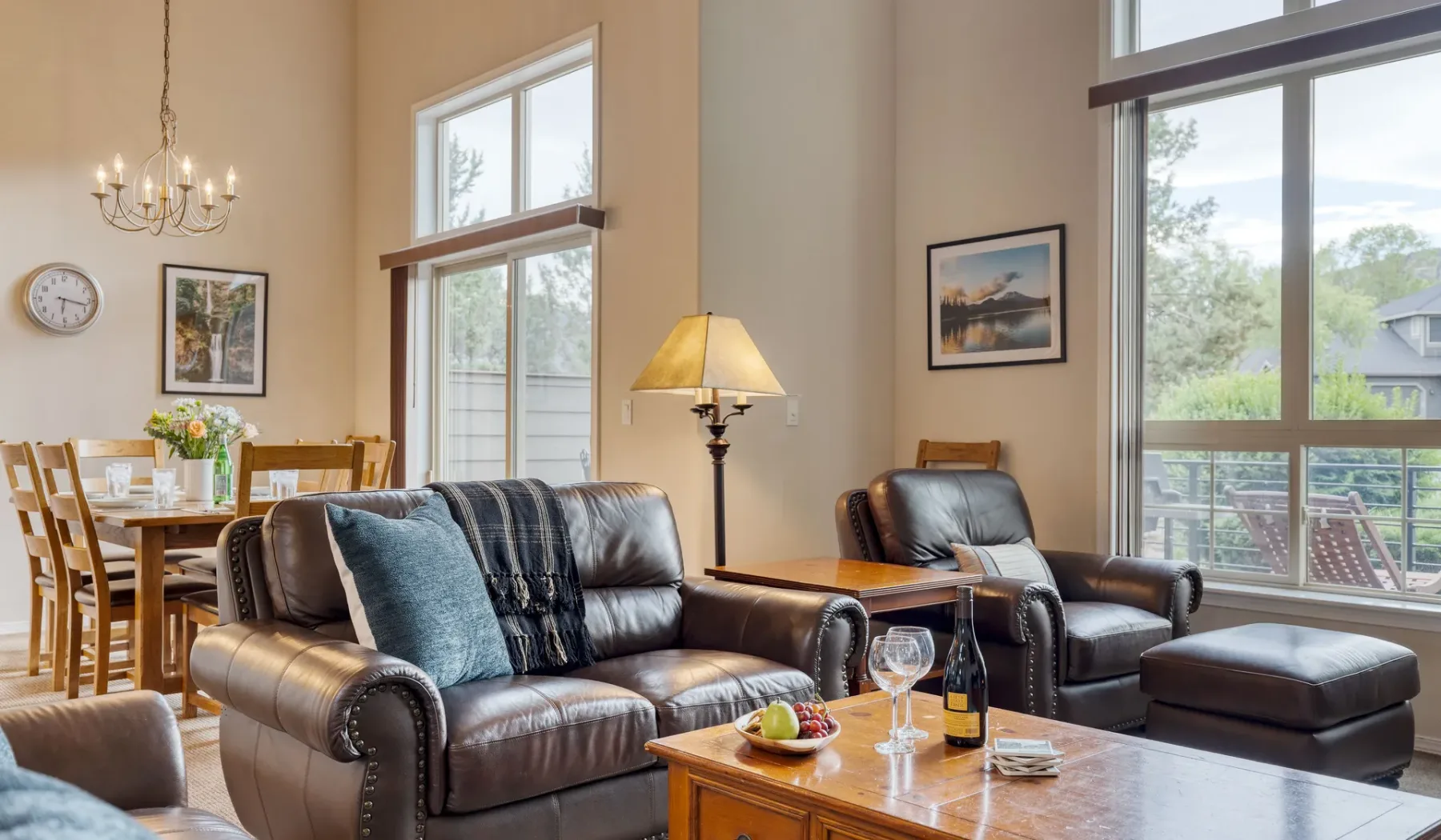 A living room with seating beside large windows and a dining area.