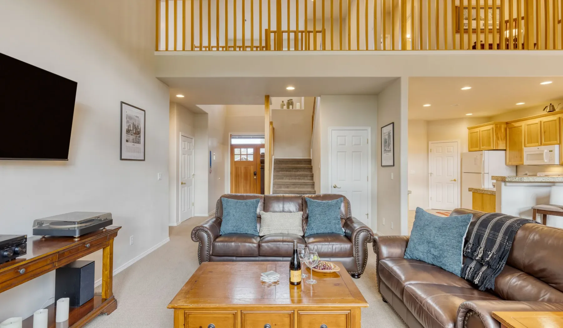 A living room with seating and a wooden coffee table, beside an open kitchen.