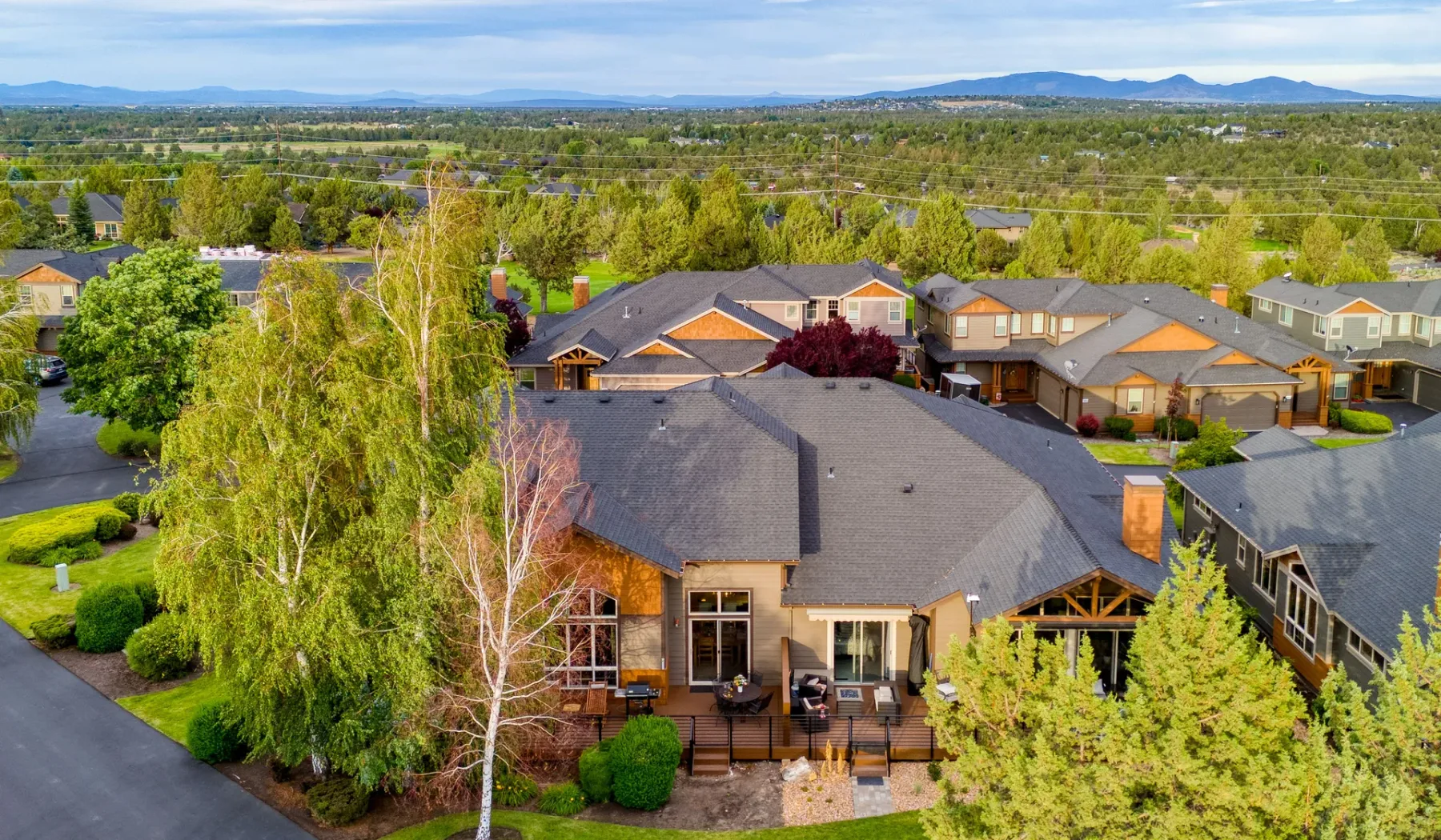 An aerial view of a residential neighborhood with homes, trees, and distant hills.