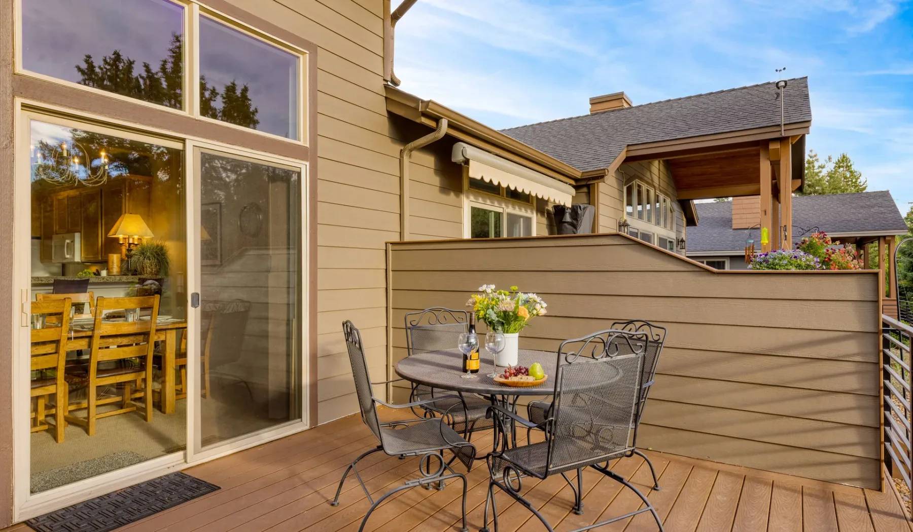 An outdoor deck has a metal dining set beside the house.