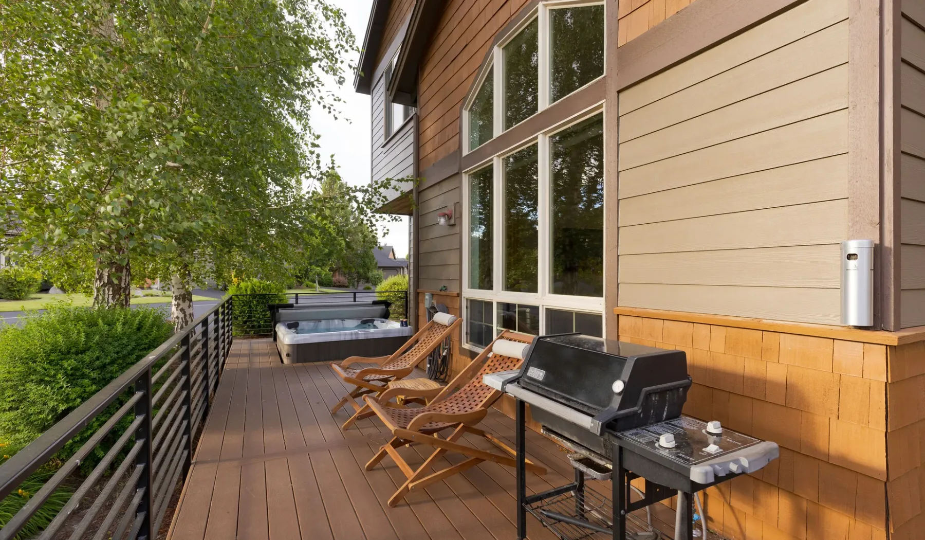 An outdoor deck with lounge seating and a barbecue beside the house.