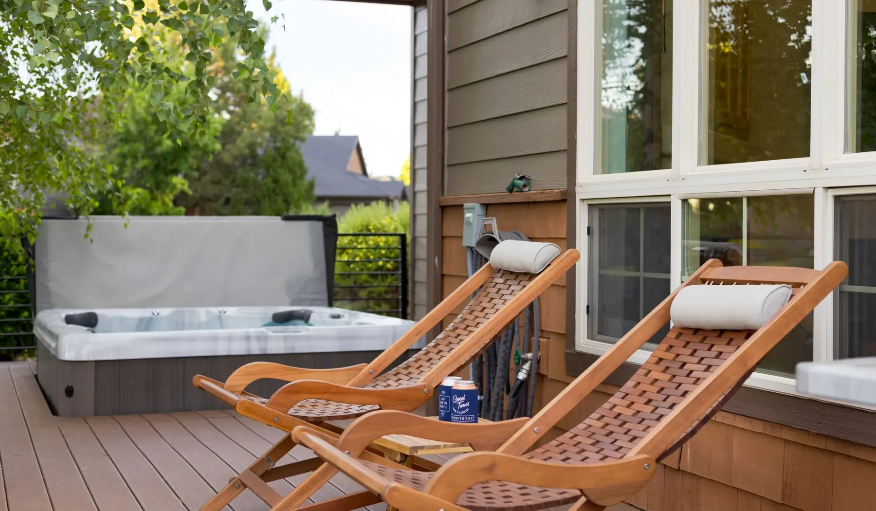 A wooden deck features two reclining lounge chairs beside a hot tub.