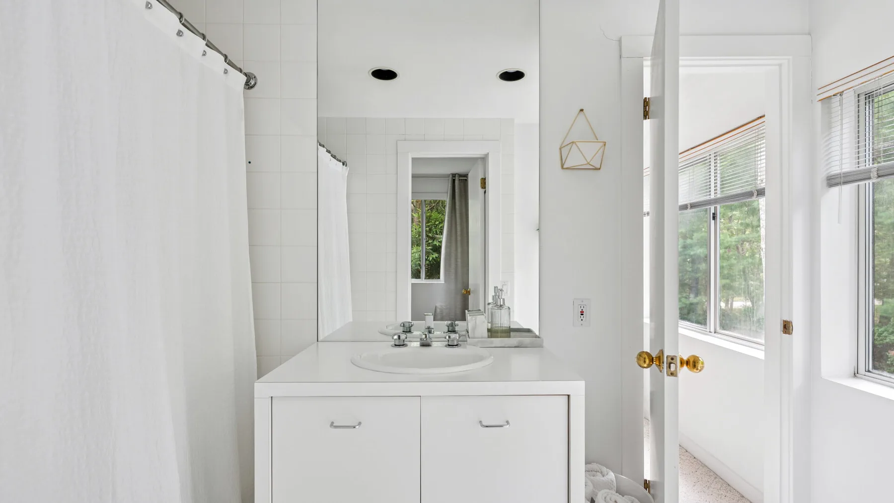Un baño luminoso con lavabo, espejo y cortina de ducha.