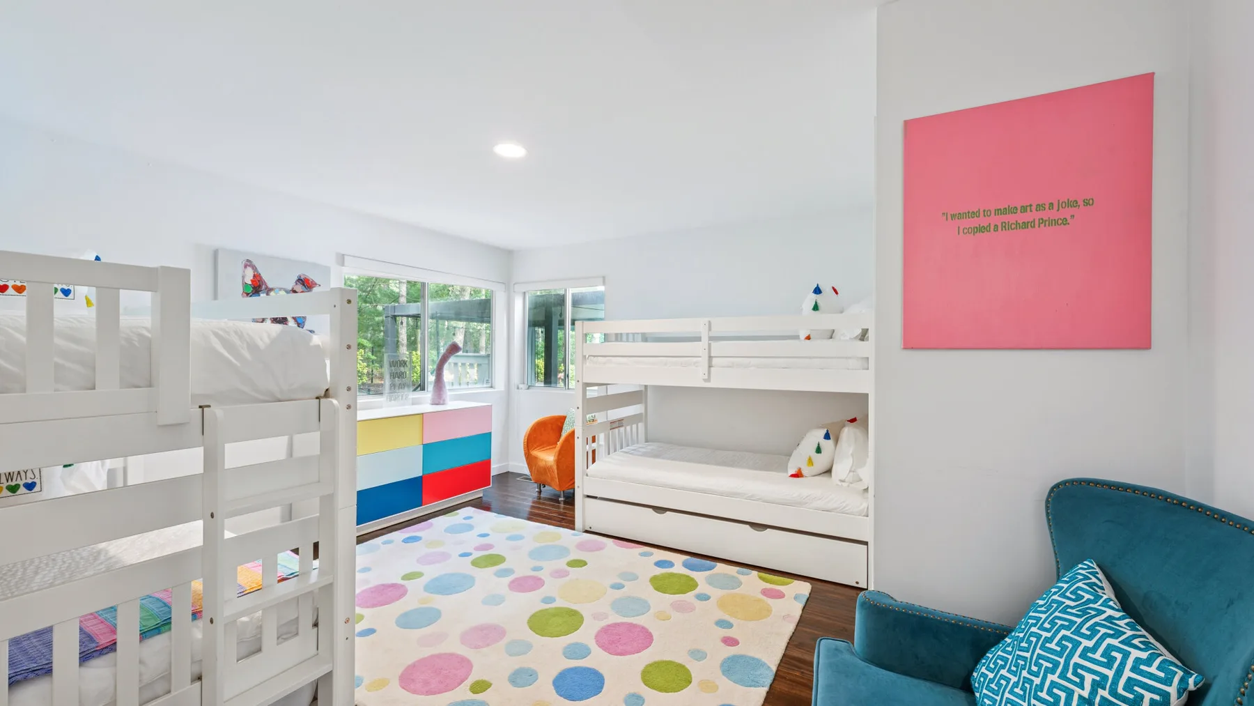 Un dormitorio luminoso con literas blancas y una alfombra de lunares coloridos.