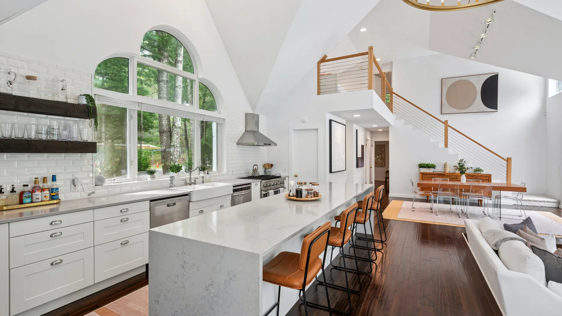 Una luminosa cocina abierta al salón, con una isla larga y una escalera.