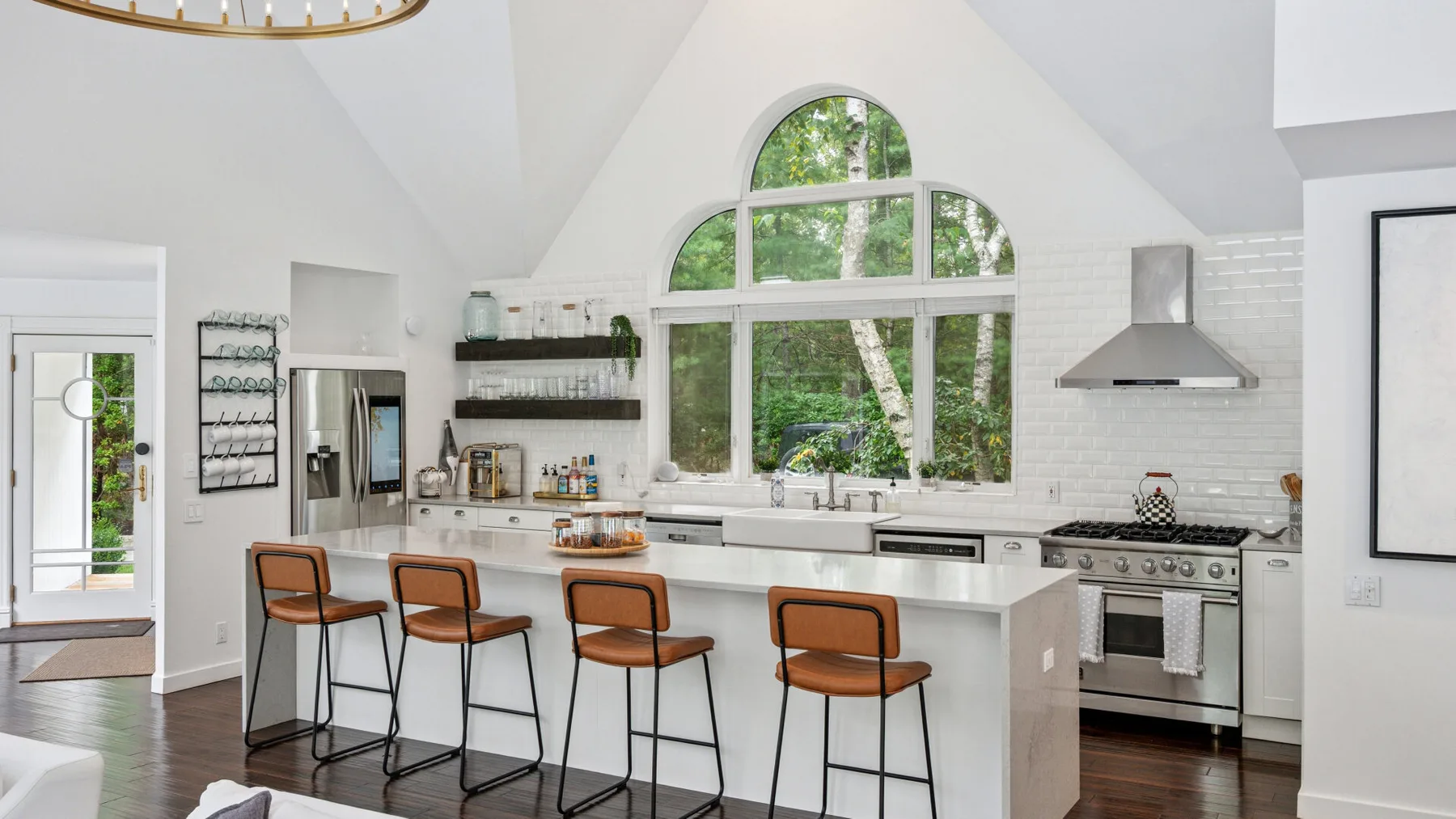 Una cocina luminosa con una isla central, asientos altos y grandes ventanas arqueadas.