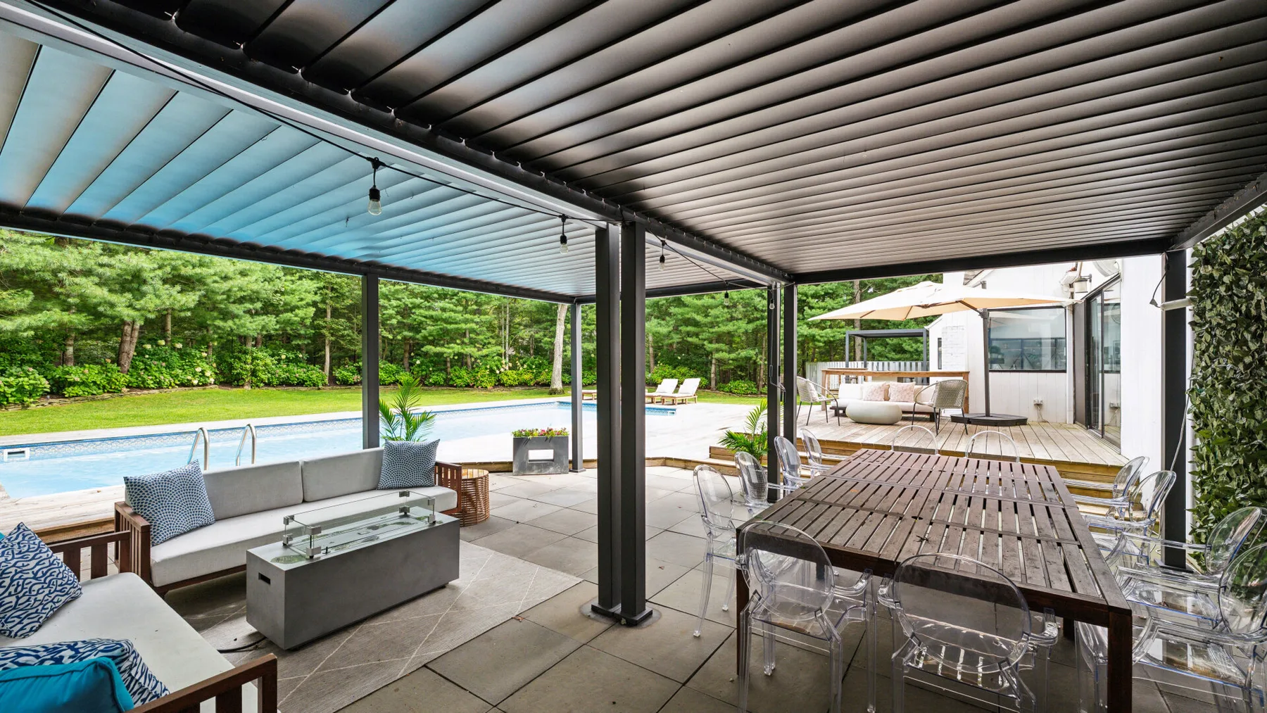 Un patio exterior cubierto con una mesa de comedor, asientos y vistas a la piscina.