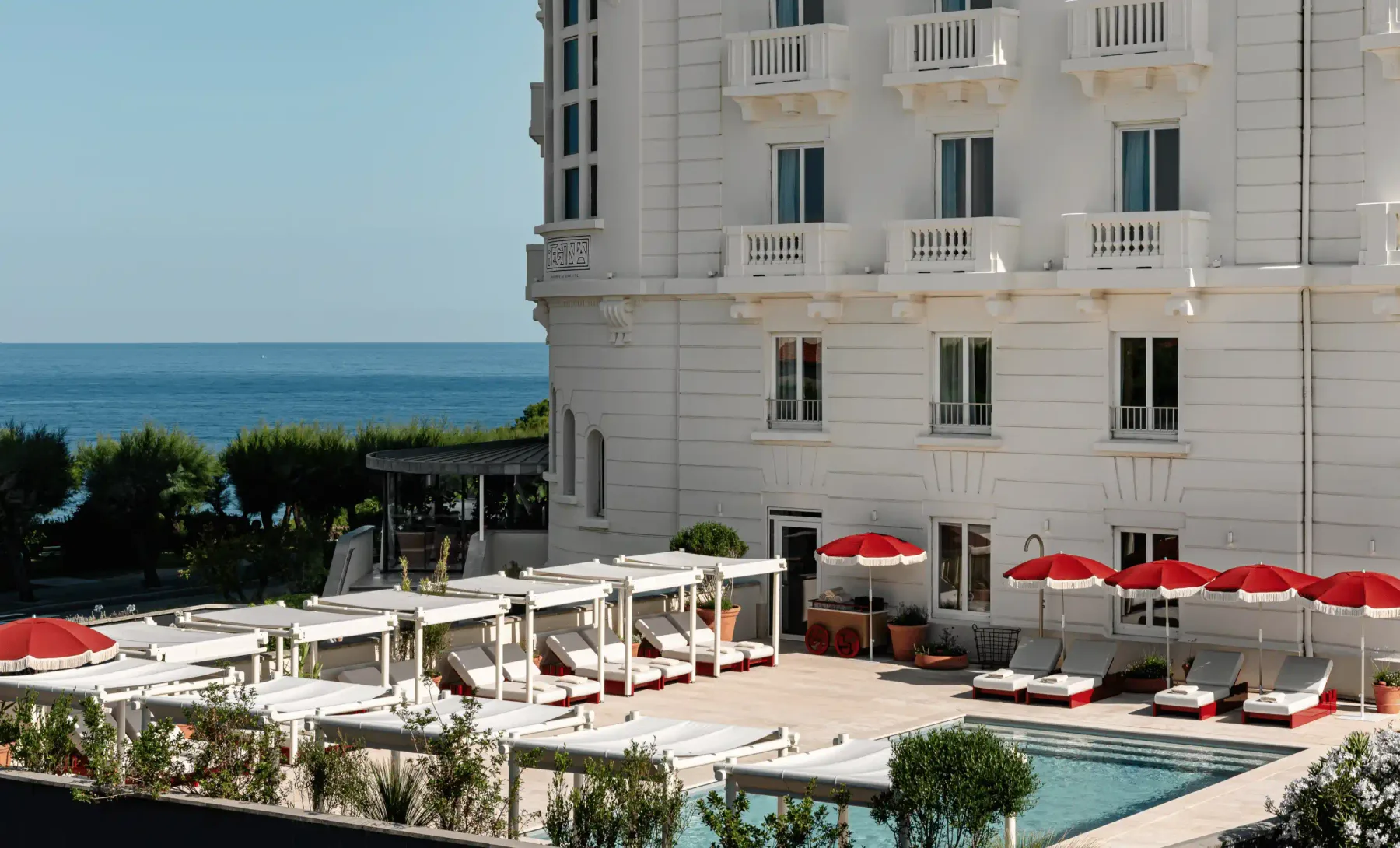 Exterior del hotel junto a la piscina, con el mar al fondo.