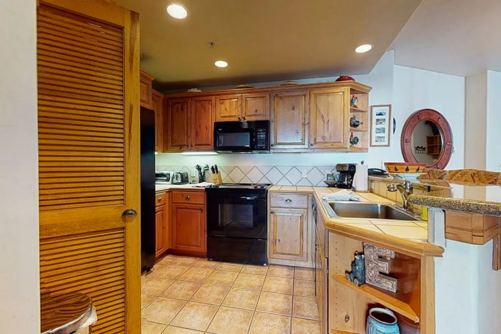 Una cocina con gabinetes de madera, un microondas y piso de baldosas.