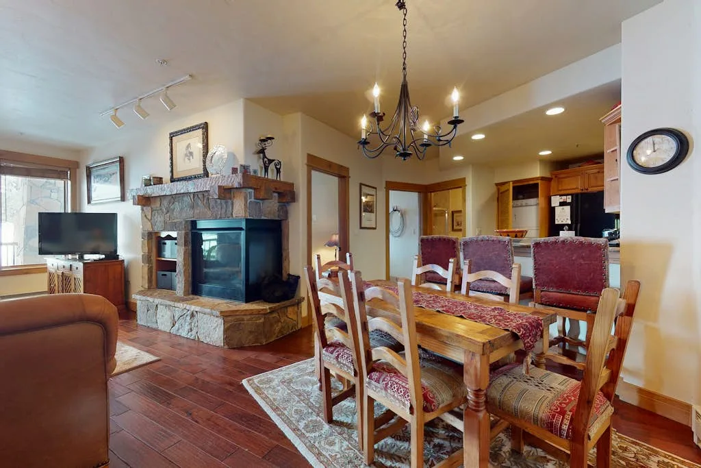 A living and dining area with a stone fireplace and a long wooden table.