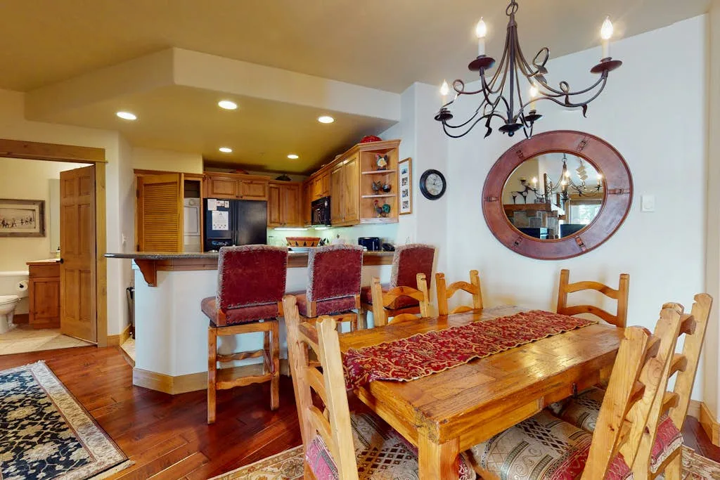 A dining area with a wooden table beside an open kitchen.