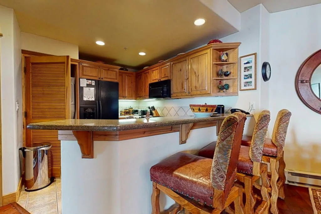 Una cocina con gabinetes de madera, una barra curva y asientos.