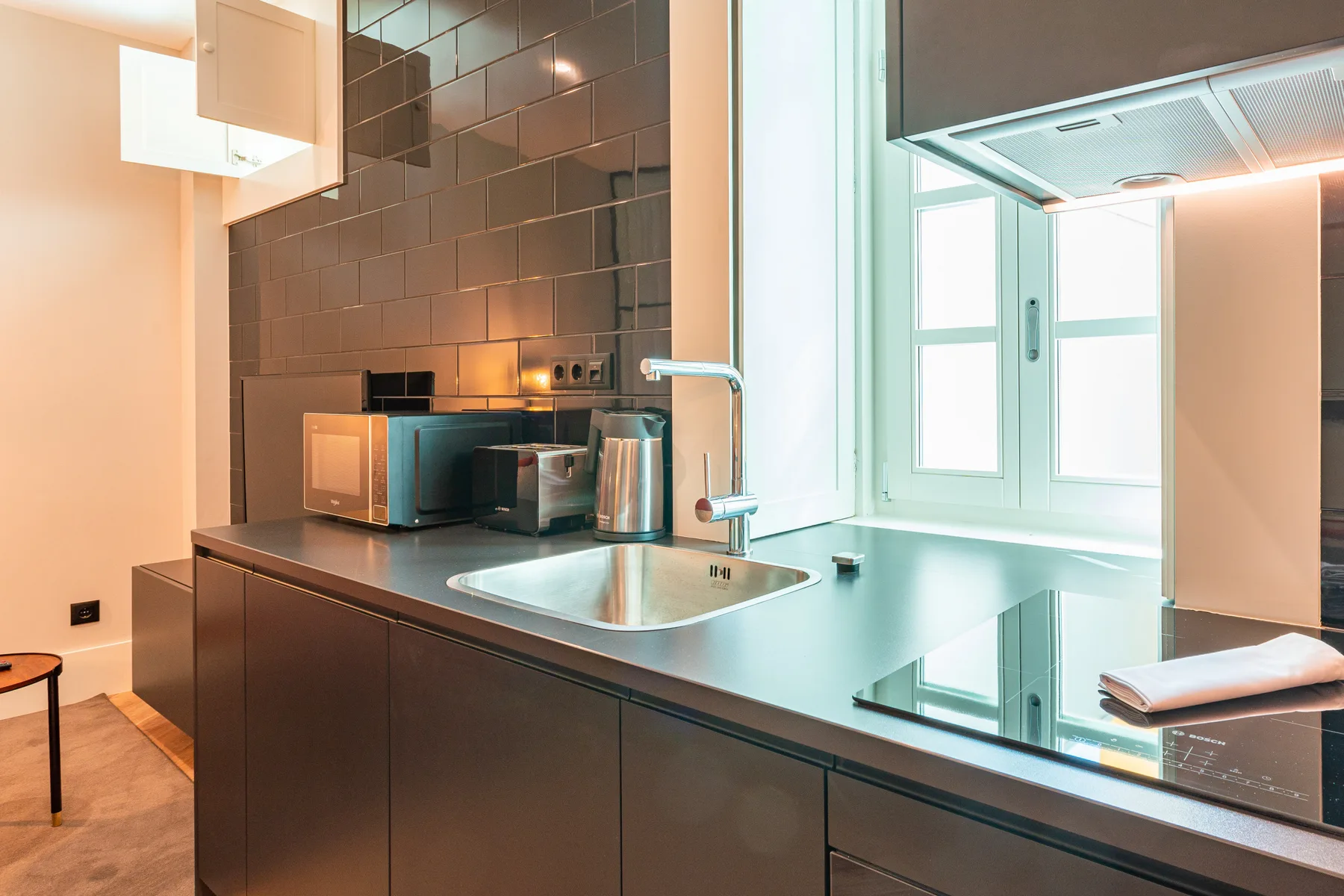 A modern kitchen with a counter, sink, and bright window.