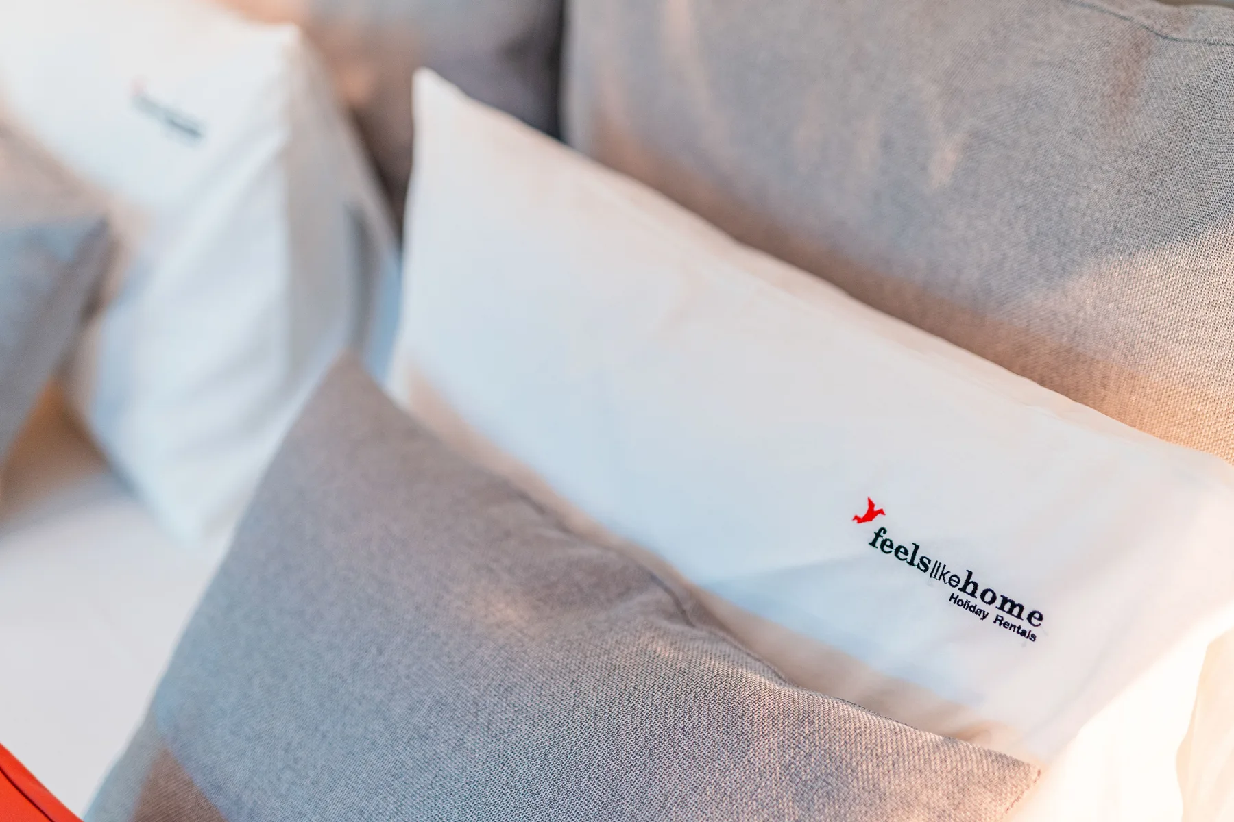 A bed with white pillows and gray bedding.