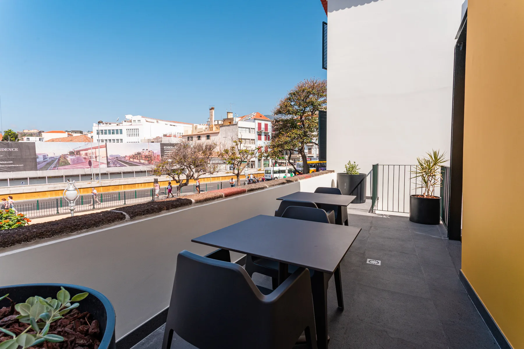 An outdoor terrace with seating overlooks nearby buildings and a street.