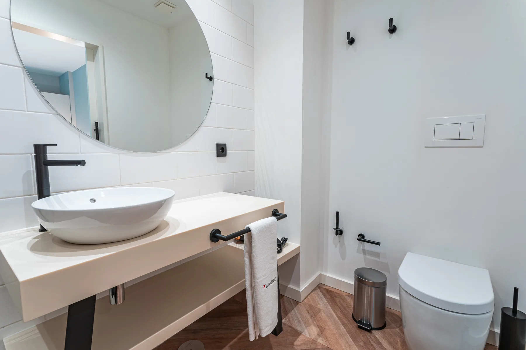 A modern bathroom vanity with a vessel sink, large mirror, and toilet.