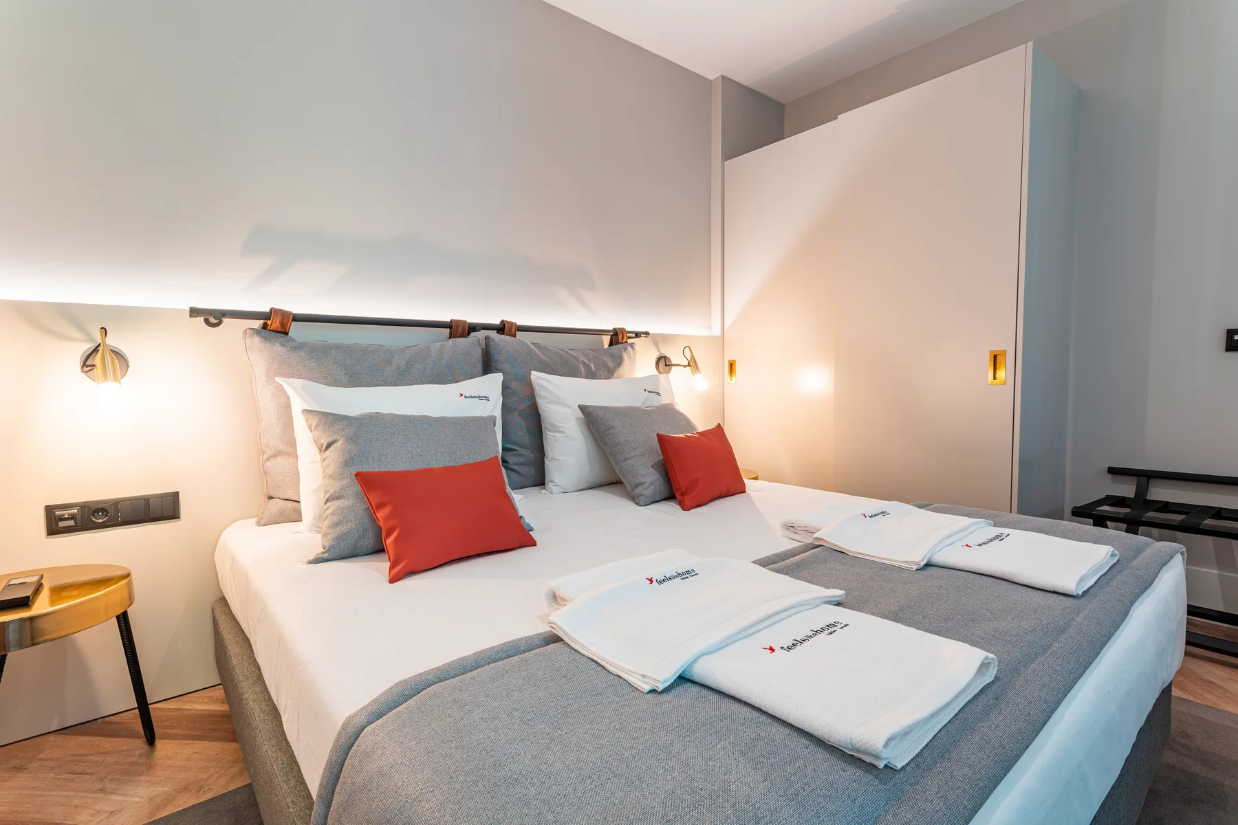 A bedroom with a neatly made bed and folded towels.