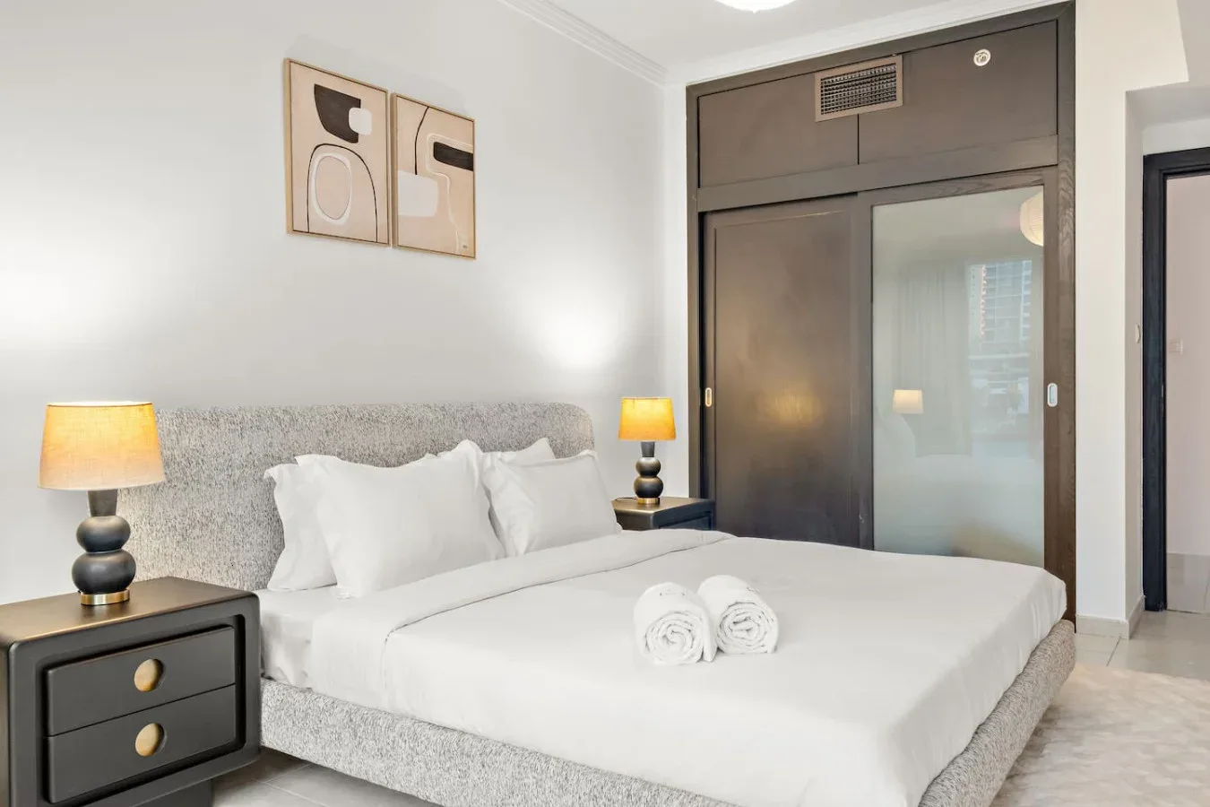 Un dormitorio con una cama grande, sábanas blancas y lámparas de noche.