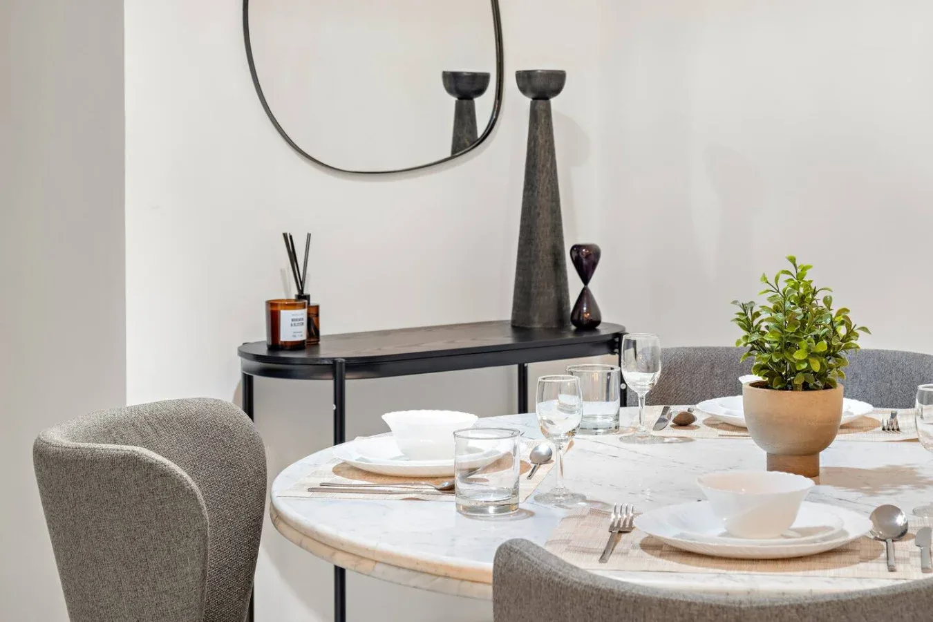 Comedor con una mesa redonda puesta para comer y una planta frondosa.