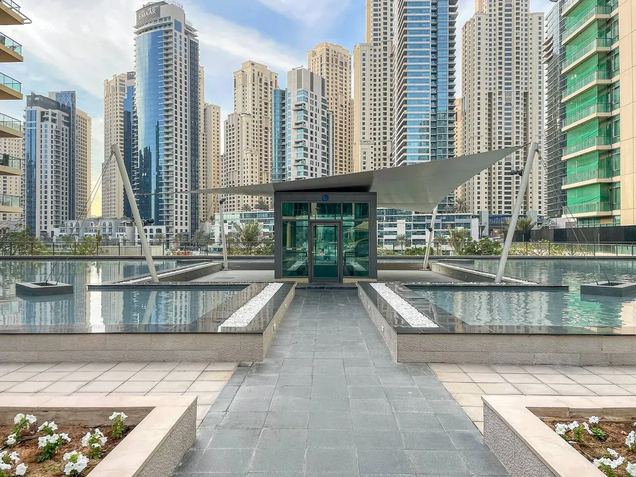 Una terraza exterior con estanques reflectantes poco profundos y un horizonte urbano.