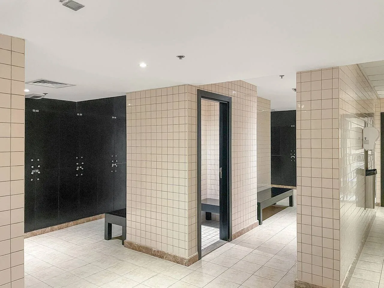Zona de baño con duchas oscuras y suelo de baldosas.