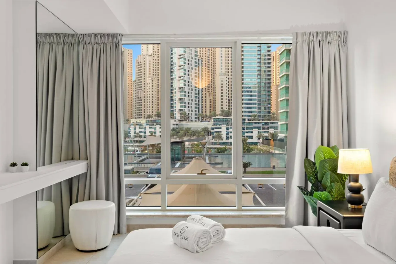 Un dormitorio luminoso con una gran ventana que da a edificios altos cercanos.