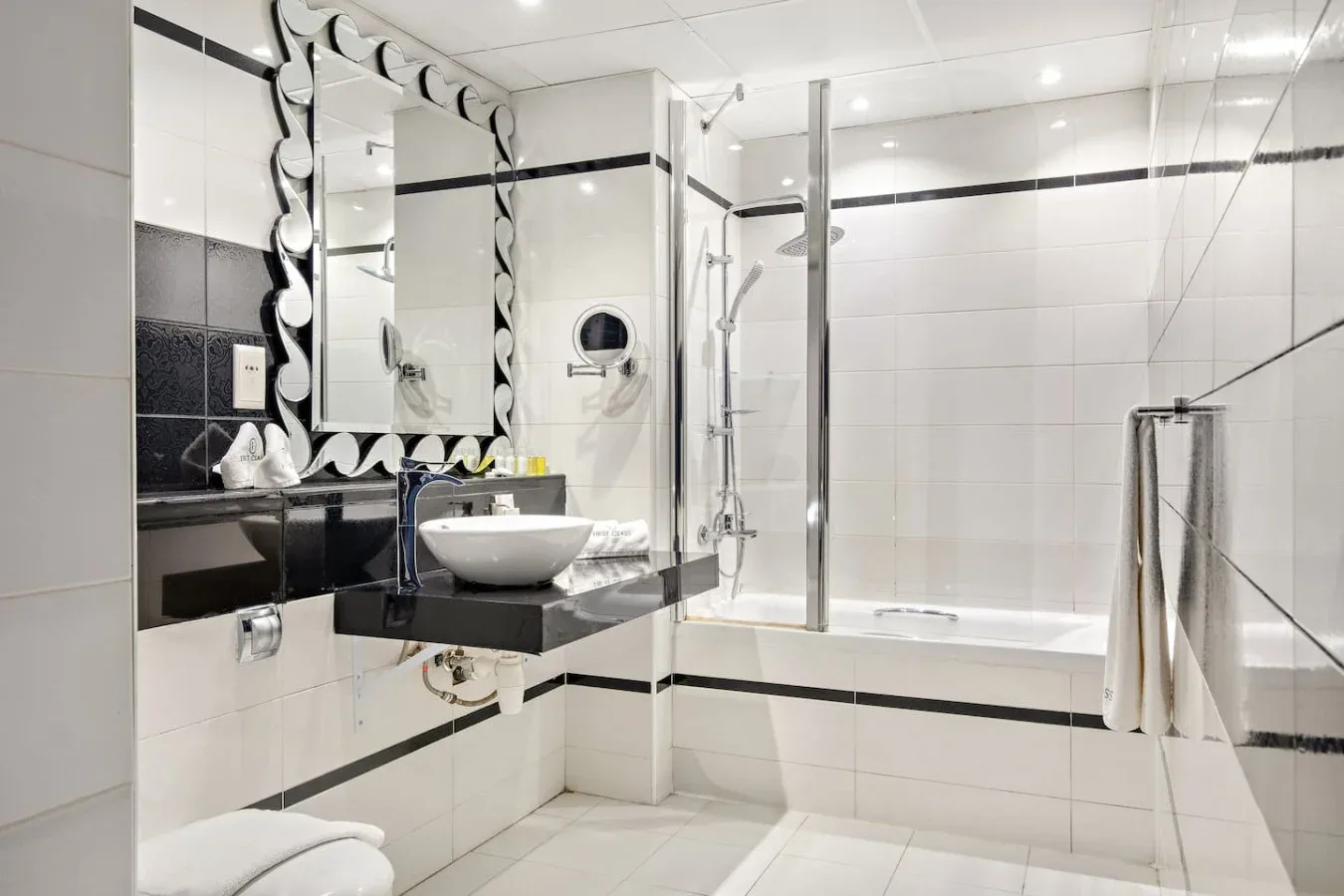 Un baño alicatado con lavabo, espejo y bañera con ducha.
