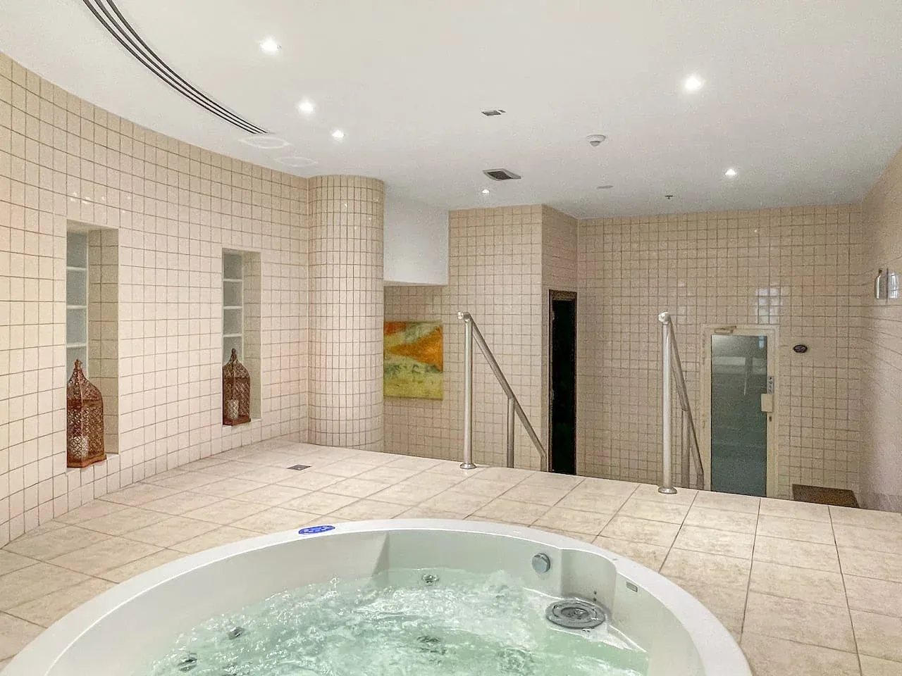 Un spa alicatado cuenta con una gran bañera de hidromasaje circular.