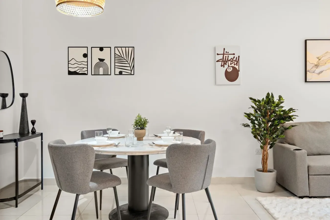 Un comedor con una mesa redonda, asientos tapizados y cuadros en la pared.
