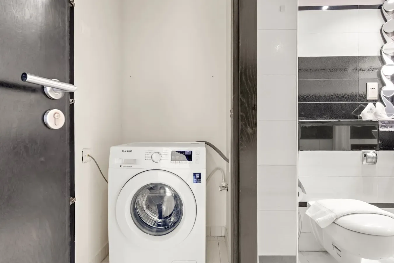 Un baño con una lavadora junto al inodoro y el lavabo.
