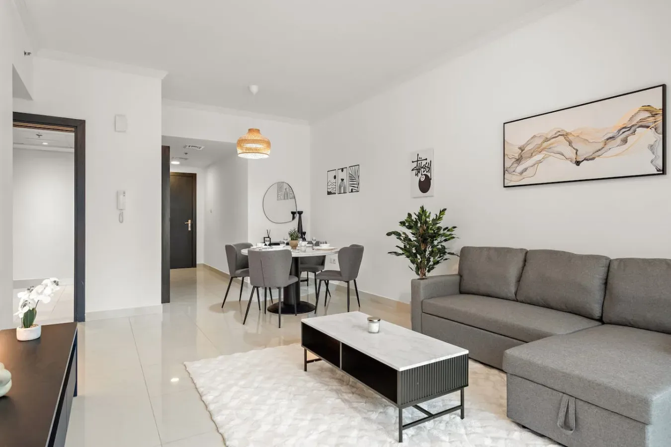 Una luminosa sala de estar y comedor con asientos grises y una mesa.
