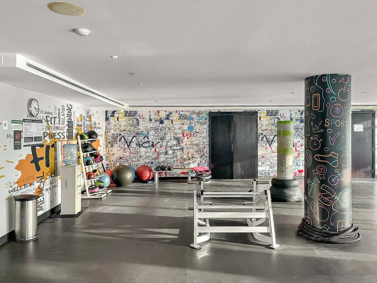 Una zona de gimnasio decorada con colores vivos, equipos de ejercicio y bancos.