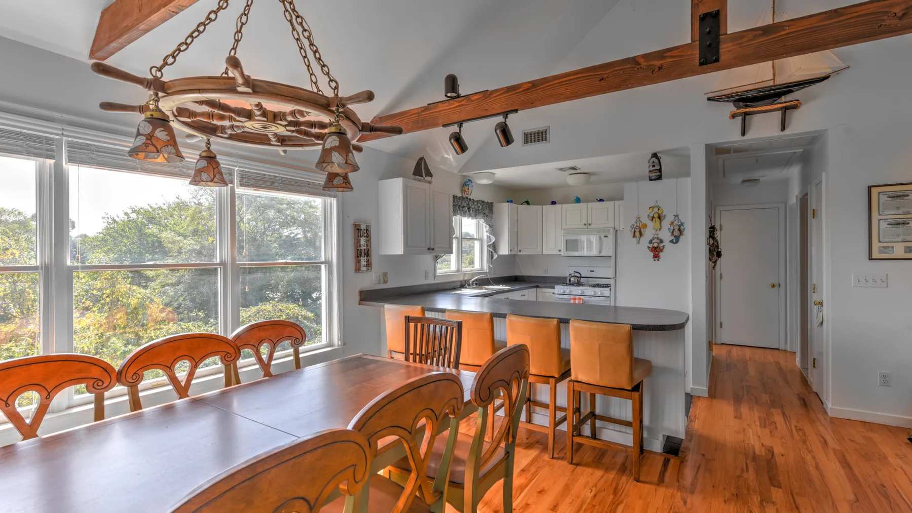 A bright kitchen and dining area with wooden tables, counters, and large windows.