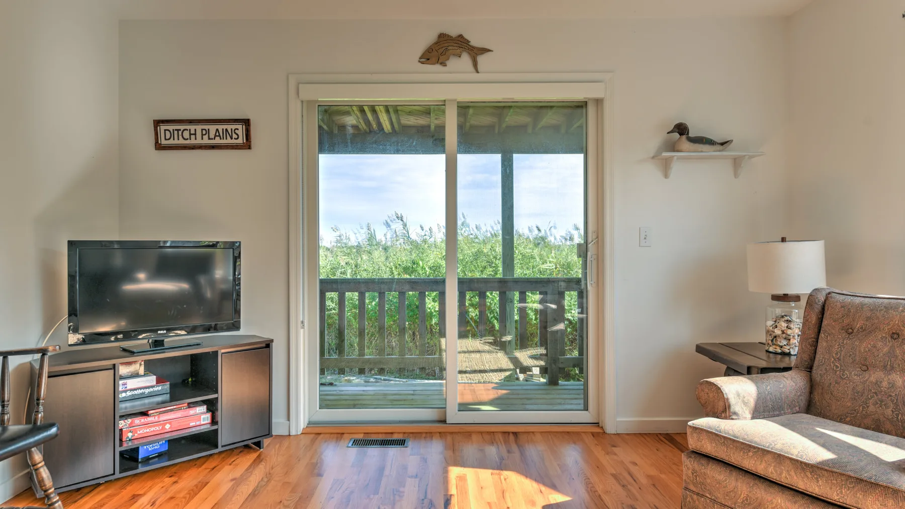 A living room with a television beside sliding glass doors opening onto a balcony.