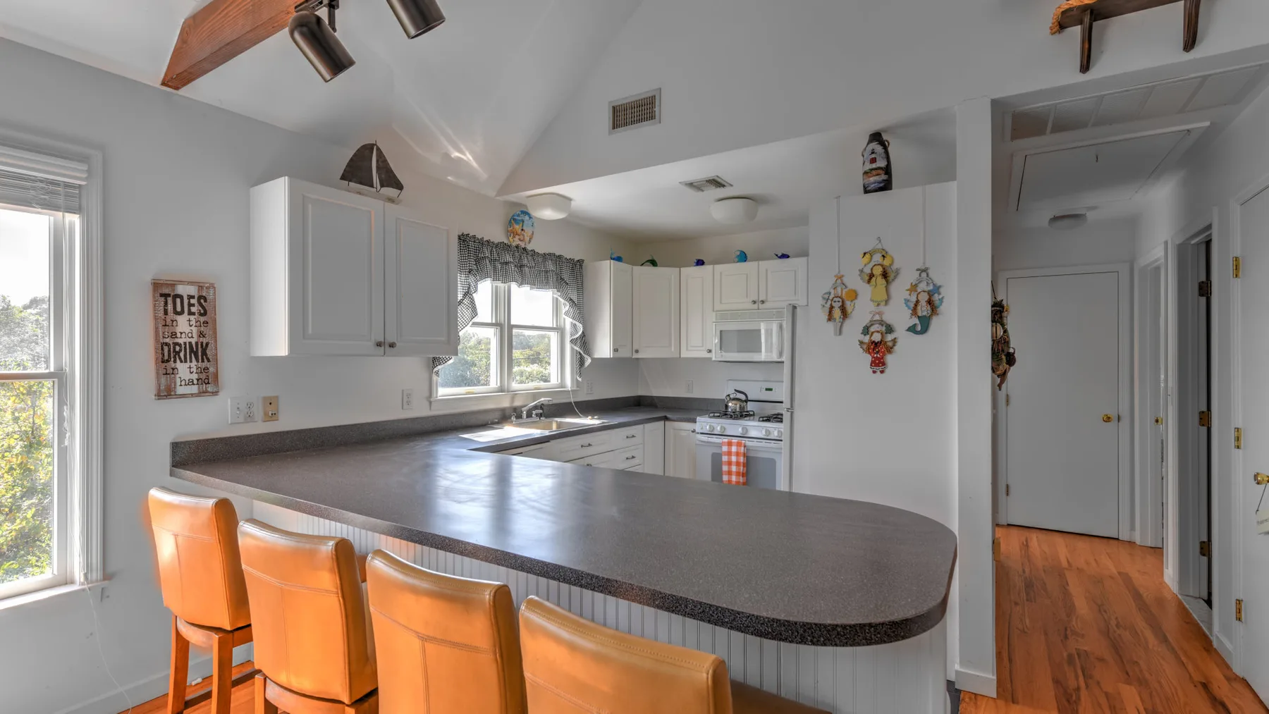 A bright kitchen with a long counter and orange bar stools.