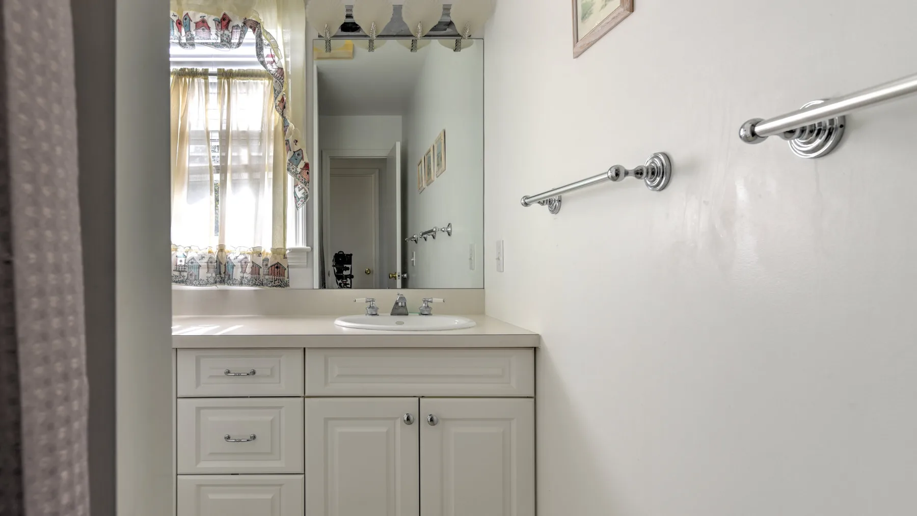 A bathroom vanity with a sink sits beneath a large mirror.