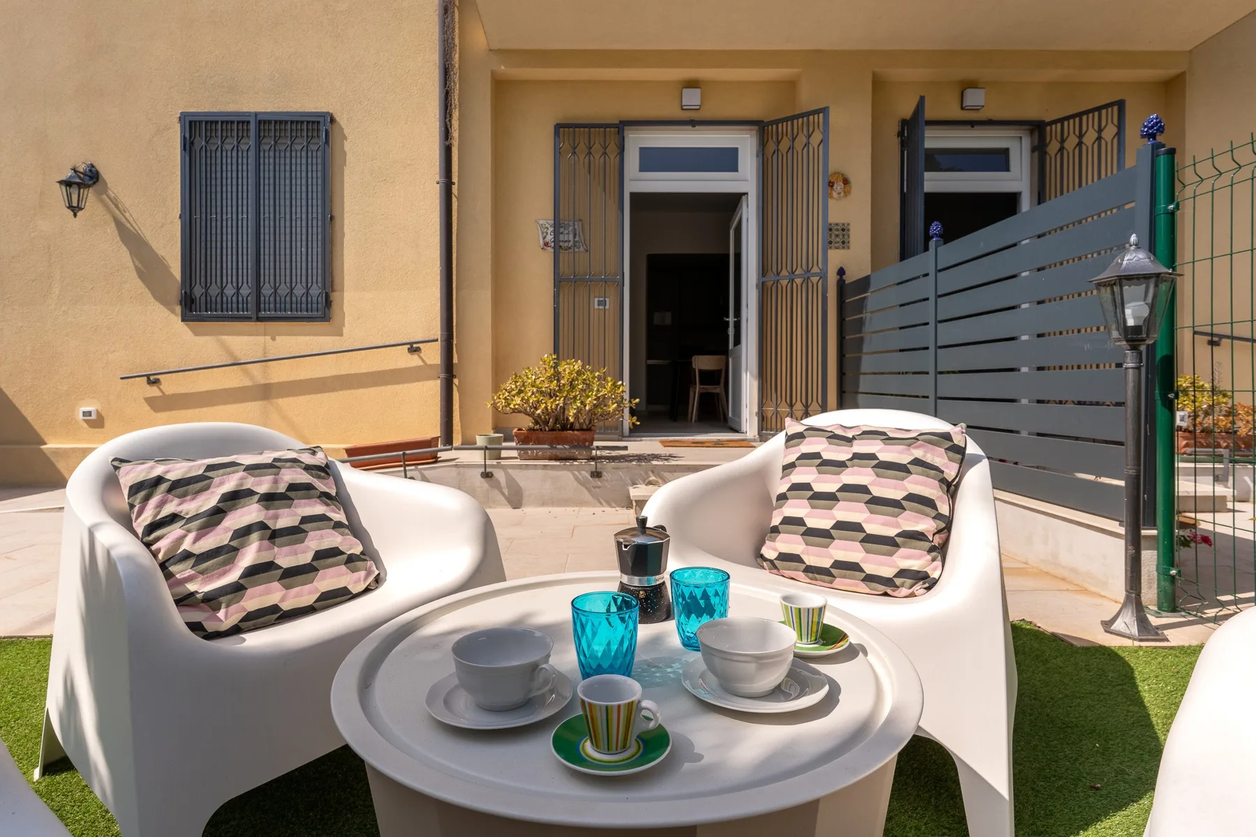 An outdoor seating area with two white chairs and a small table.