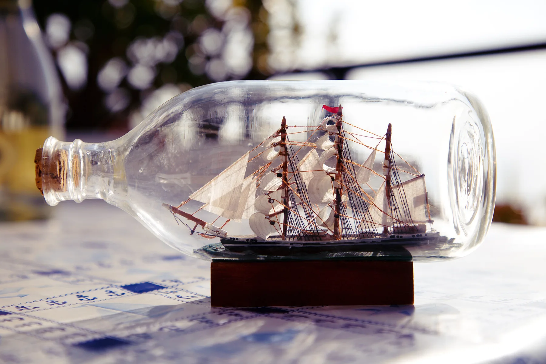 A model sailing ship is displayed inside a clear glass bottle on a table.
